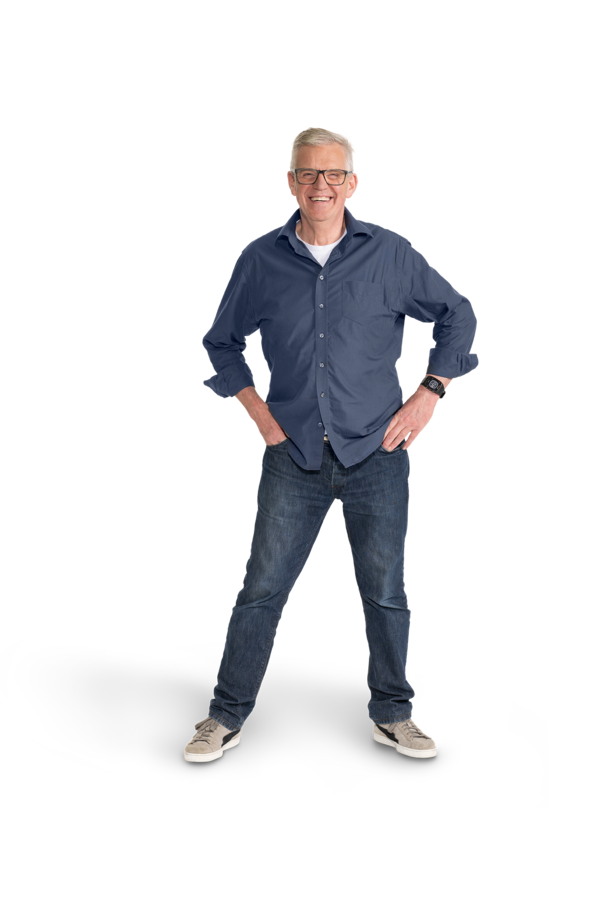 Ein älterer Mann mit grauem Haar, Brille, Jeanshose und Jeanshemd.