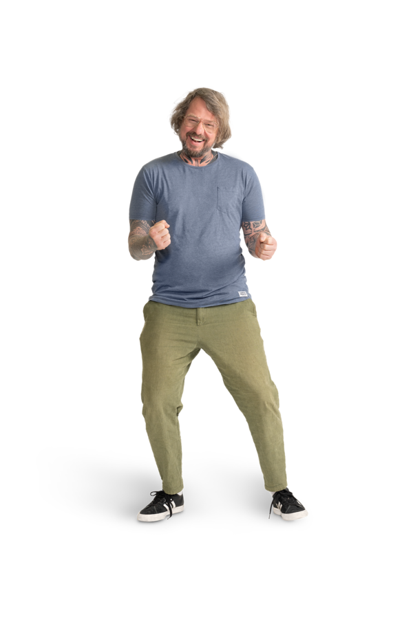 Ein Mann mit Brille, hellblauem Shirt, tätowierten Armen und khakifarbener Hose.